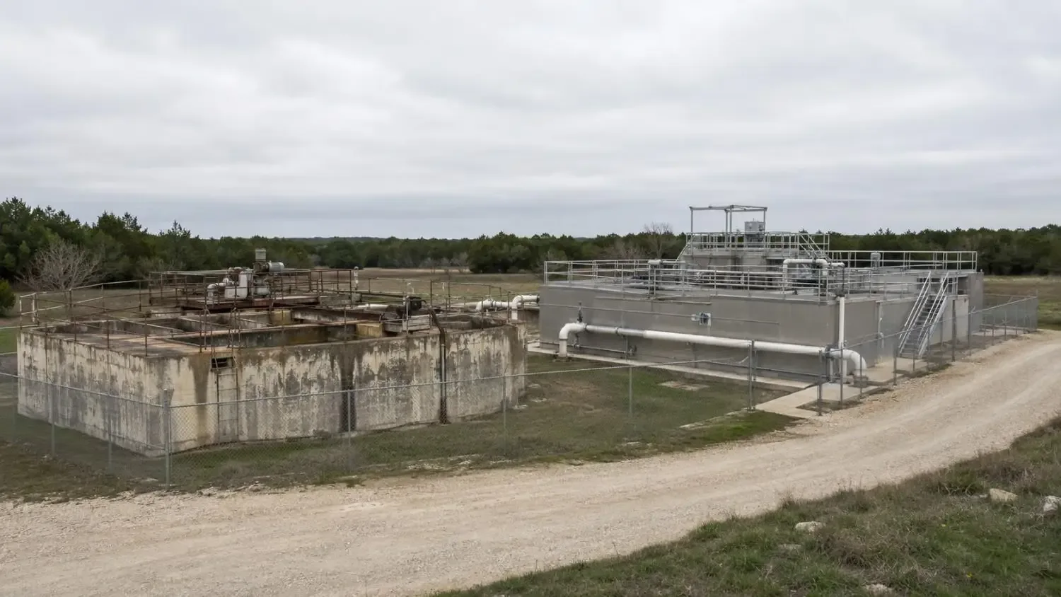 Small Texas municipal wastewater treatment plant showing aging secondary treatment infrastructure beside a newer advanced treatment upgrade addition