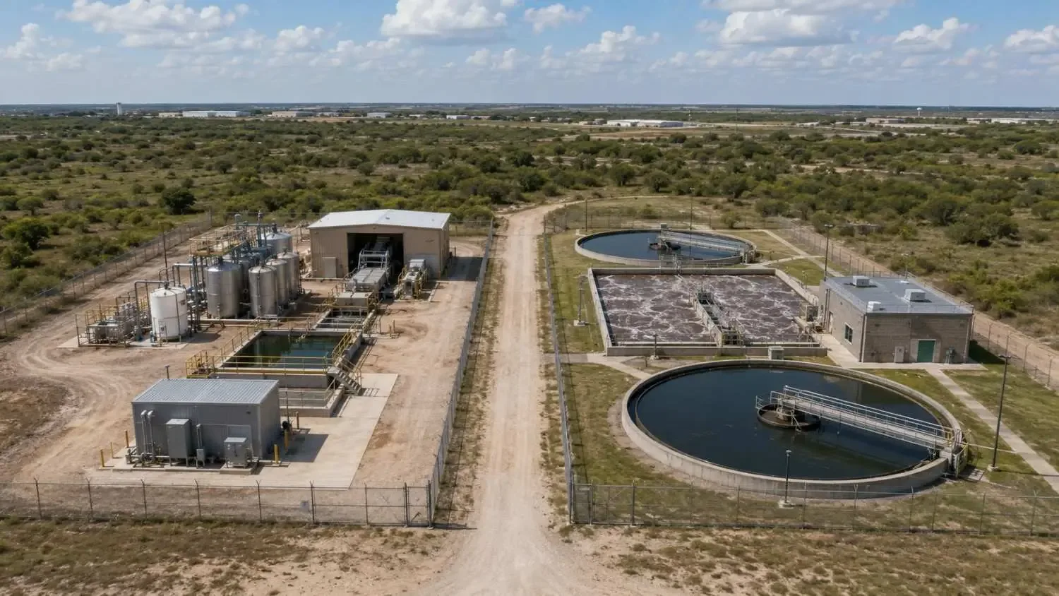 Ground-level wide shot of a Texas municipal wastewater treatment plant showing extended aeration basins with active biological treatment, clarifiers and effluent monitoring equipment.