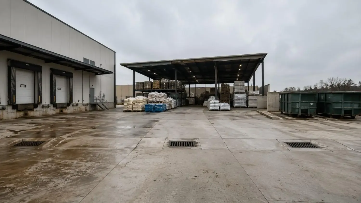 Ground-level shot of a Texas industrial facility outdoor loading dock and material storage area with stormwater drainage channels.