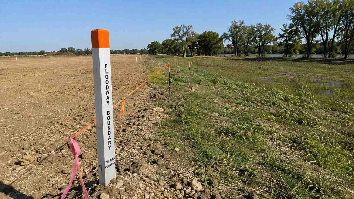 Trinity River floodway boundary marker at riverside development parcel edge.